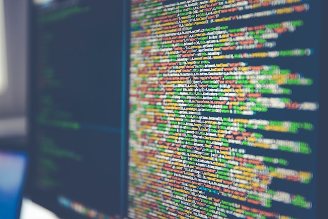 Black computer screen with rainbow-colored computer code